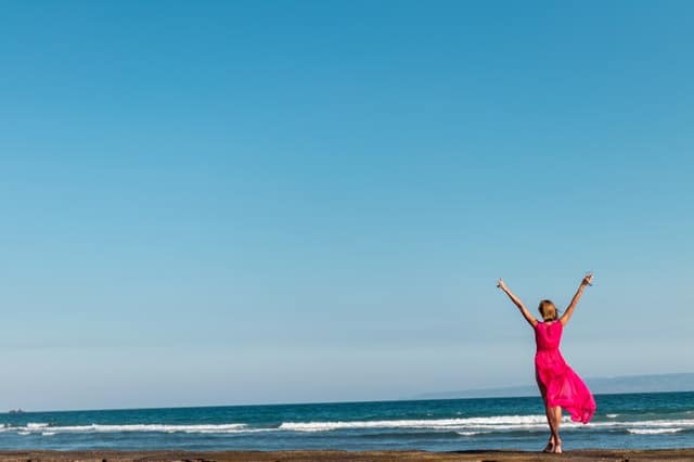 una donna in abito rosso in piedi sulla costa